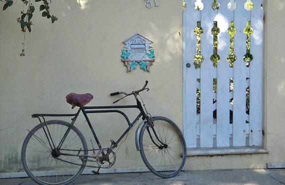 Bicicleta encostada no muro, próximo ao portão da casa
